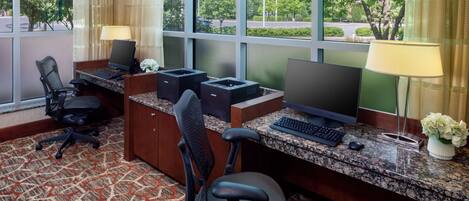 A hotel reception desk with two computer monitors, a keyboard, a mouse, and two office chairs.