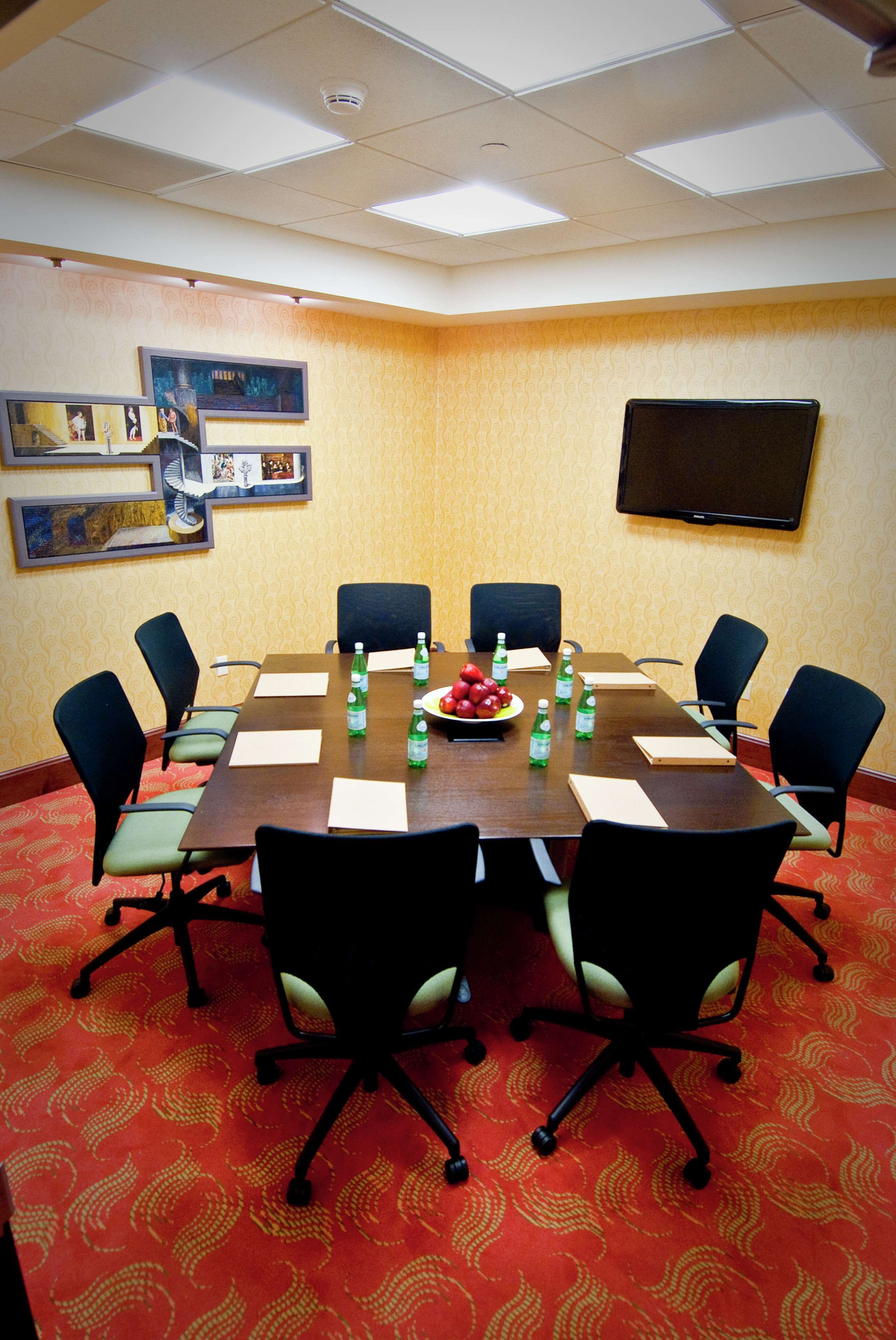 A conference room with a long table, eight chairs, water bottles, and a fruit plate.