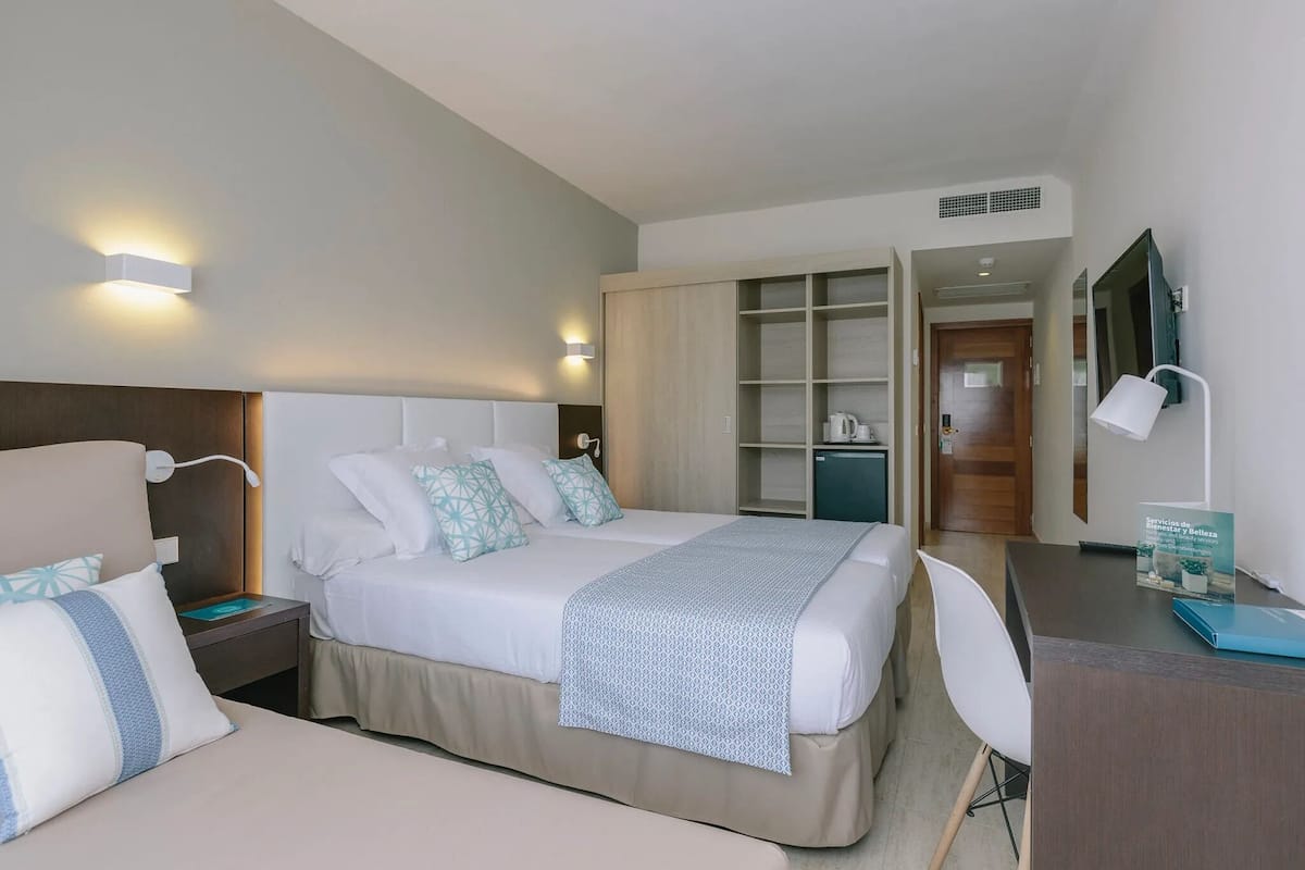 Une chambre d’hôtel comprenant un lit, des tables de chevet, un bureau et une armoire.