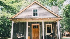 A rustic wooden cabin with a porch, a central door, and a small window. - Stevenson Ridge (Spotsylvania)