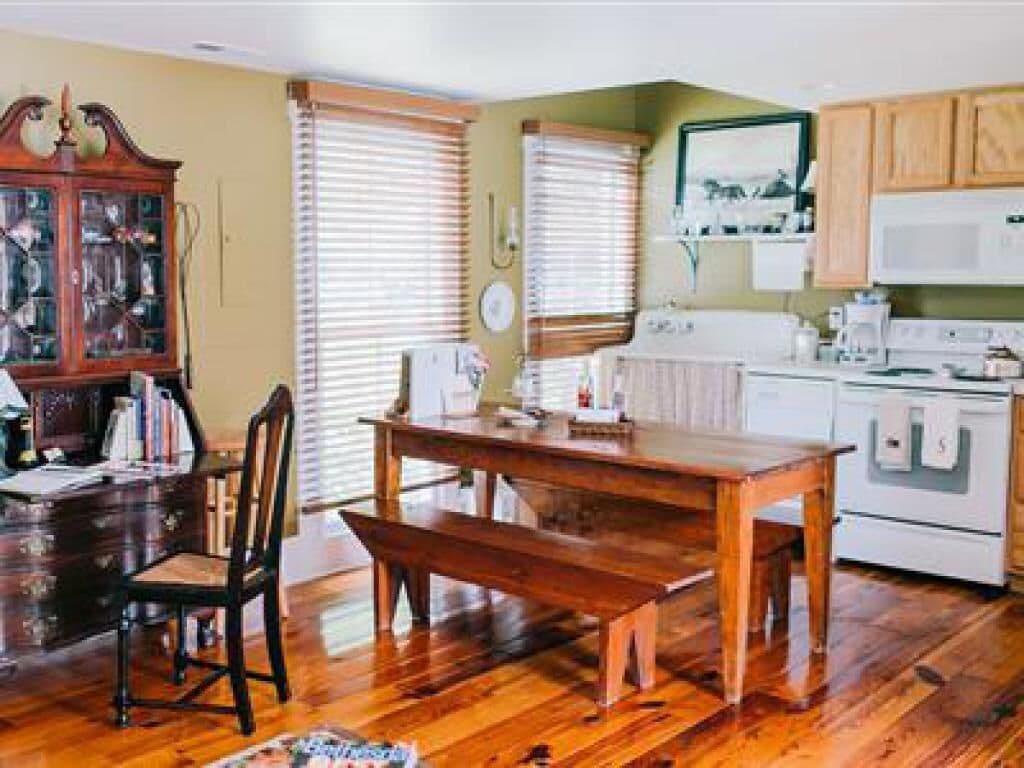 Una cucina con mobili in legno, un piano cottura bianco e un tavolo da pranzo con sedie.