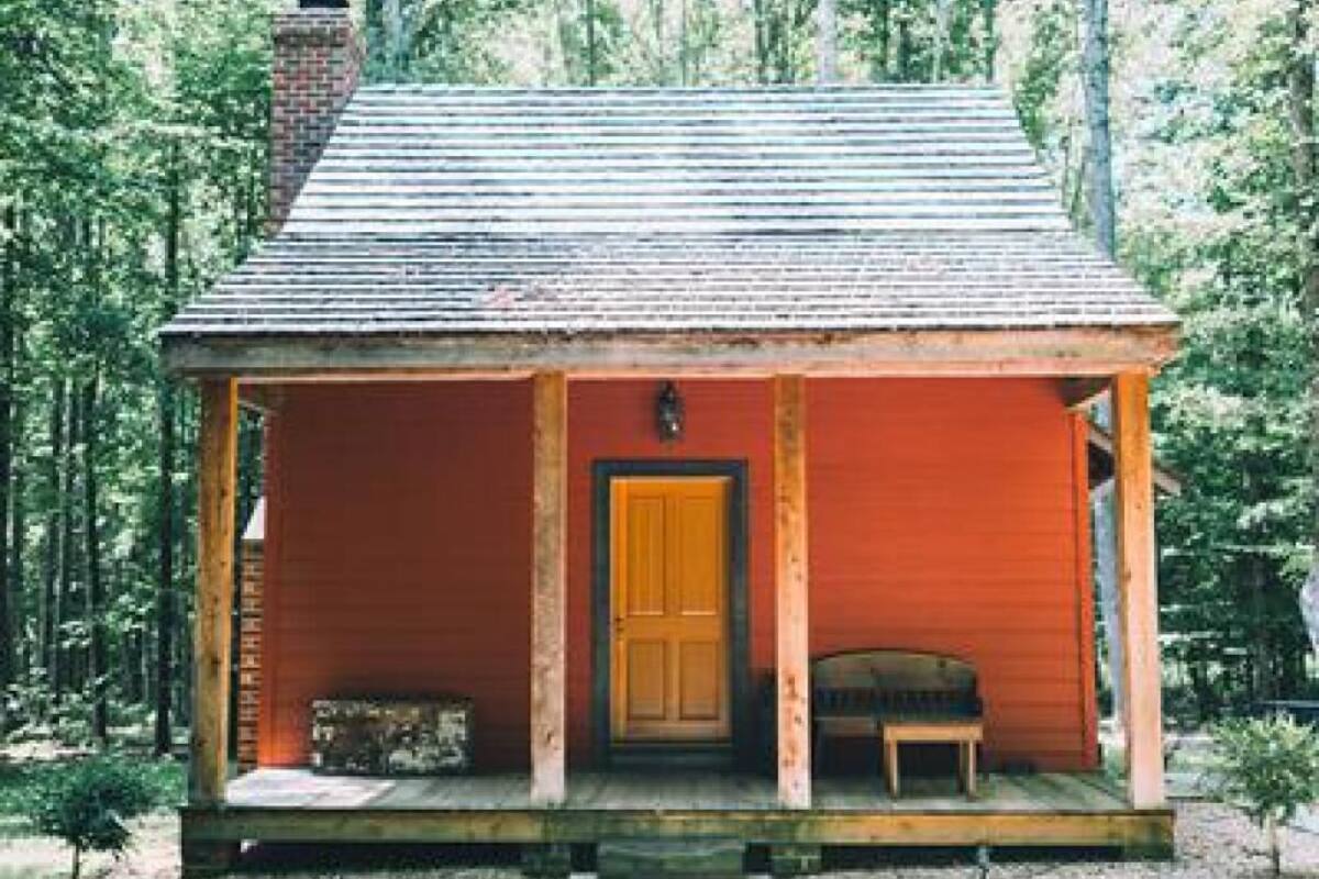 A small, single-story cabin with a wooden porch and a central door.