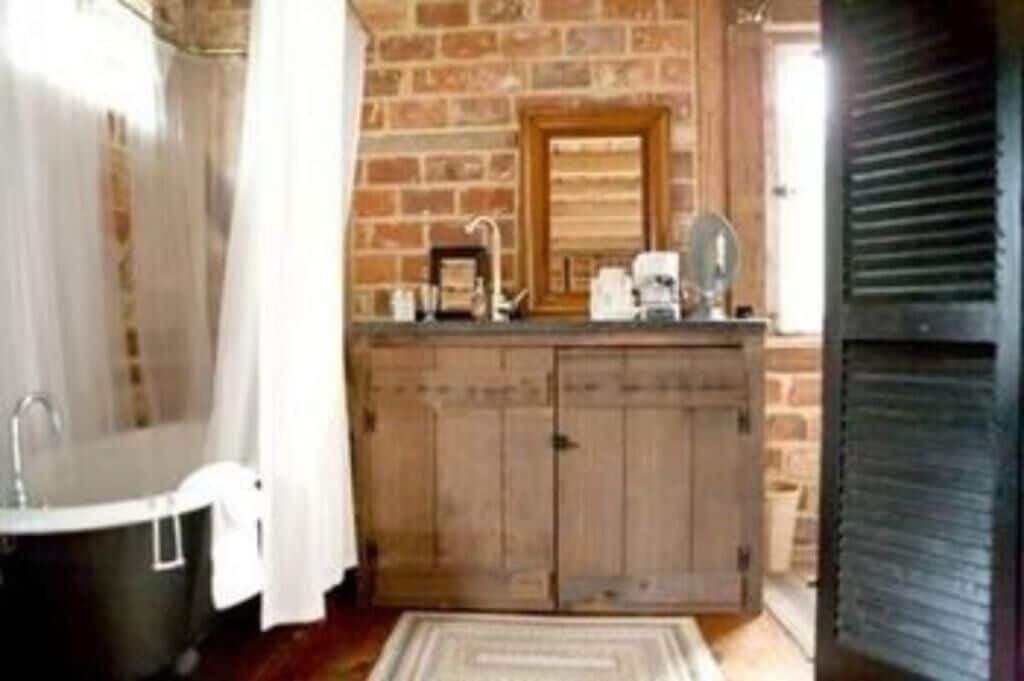 A bathroom with a wooden vanity, a black bathtub, and a brick wall.