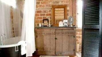 A bathroom with a wooden vanity, a black bathtub, and a brick wall.