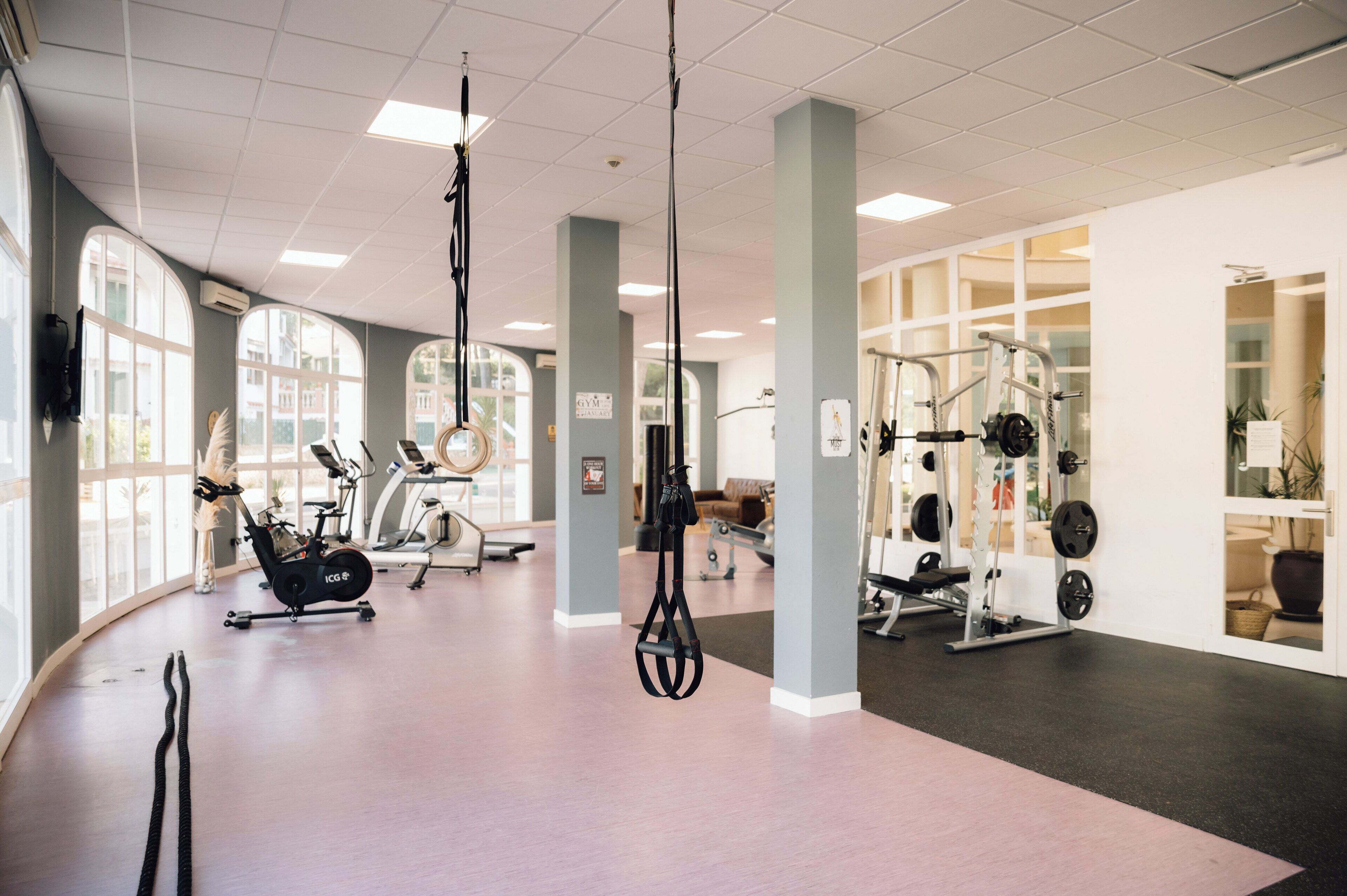 Une salle de sport équipée de machines de cardio, de matériel de musculation et dotée de grandes fenêtres.