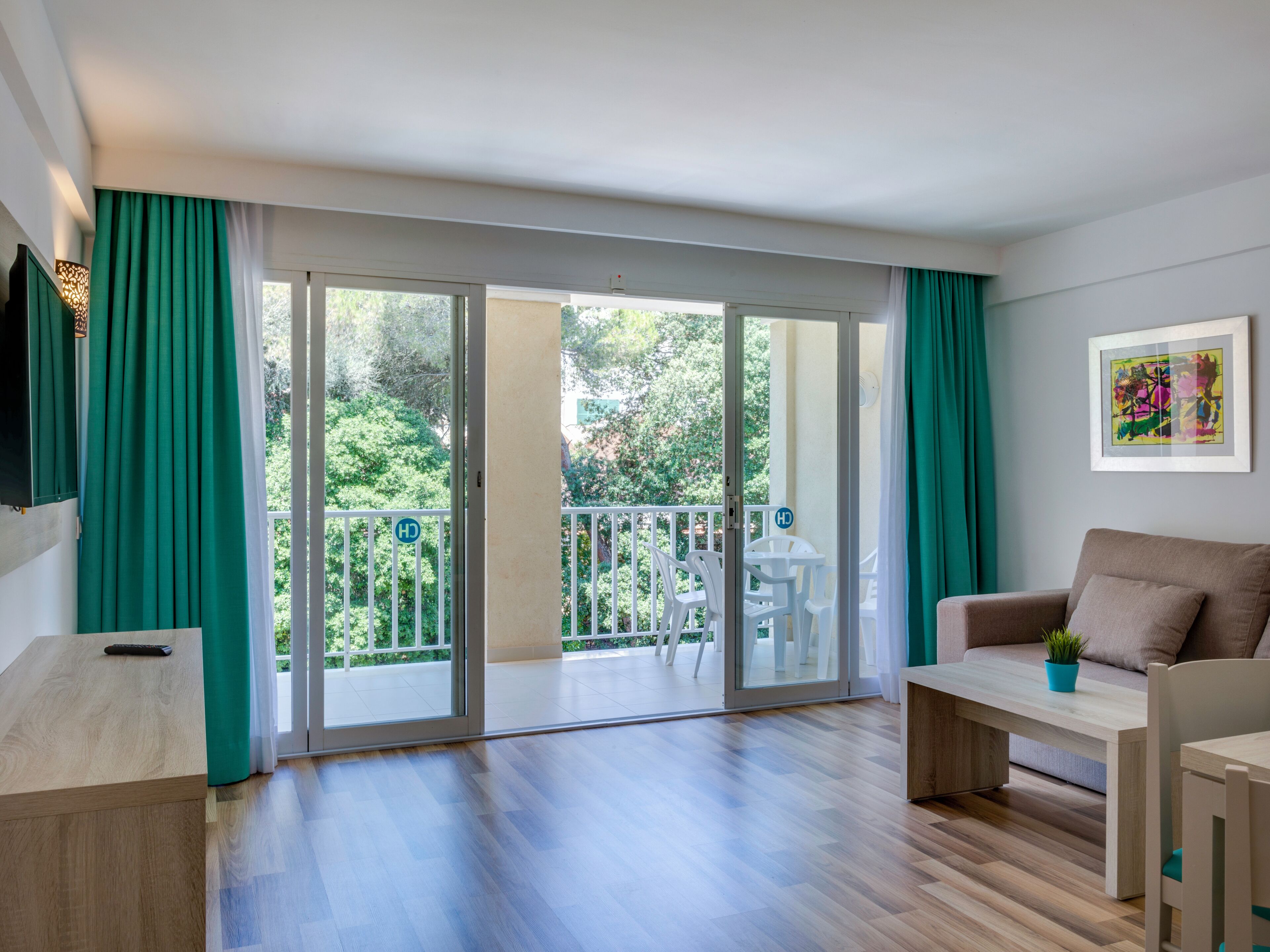 Un salon moderne avec un canapé, une table basse et un balcon offrant une vue sur la verdure.