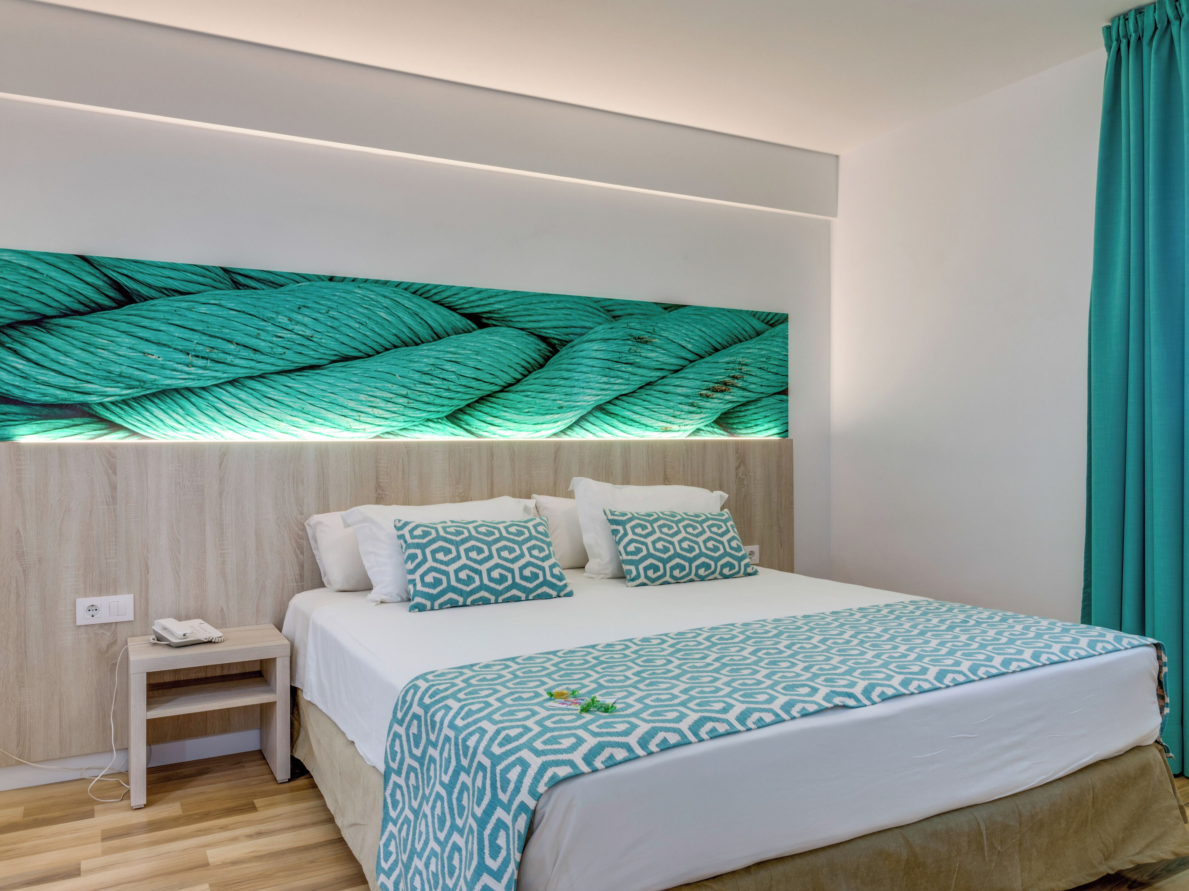 A modern bedroom with a bed, bedside table, and a wall-mounted light fixture.