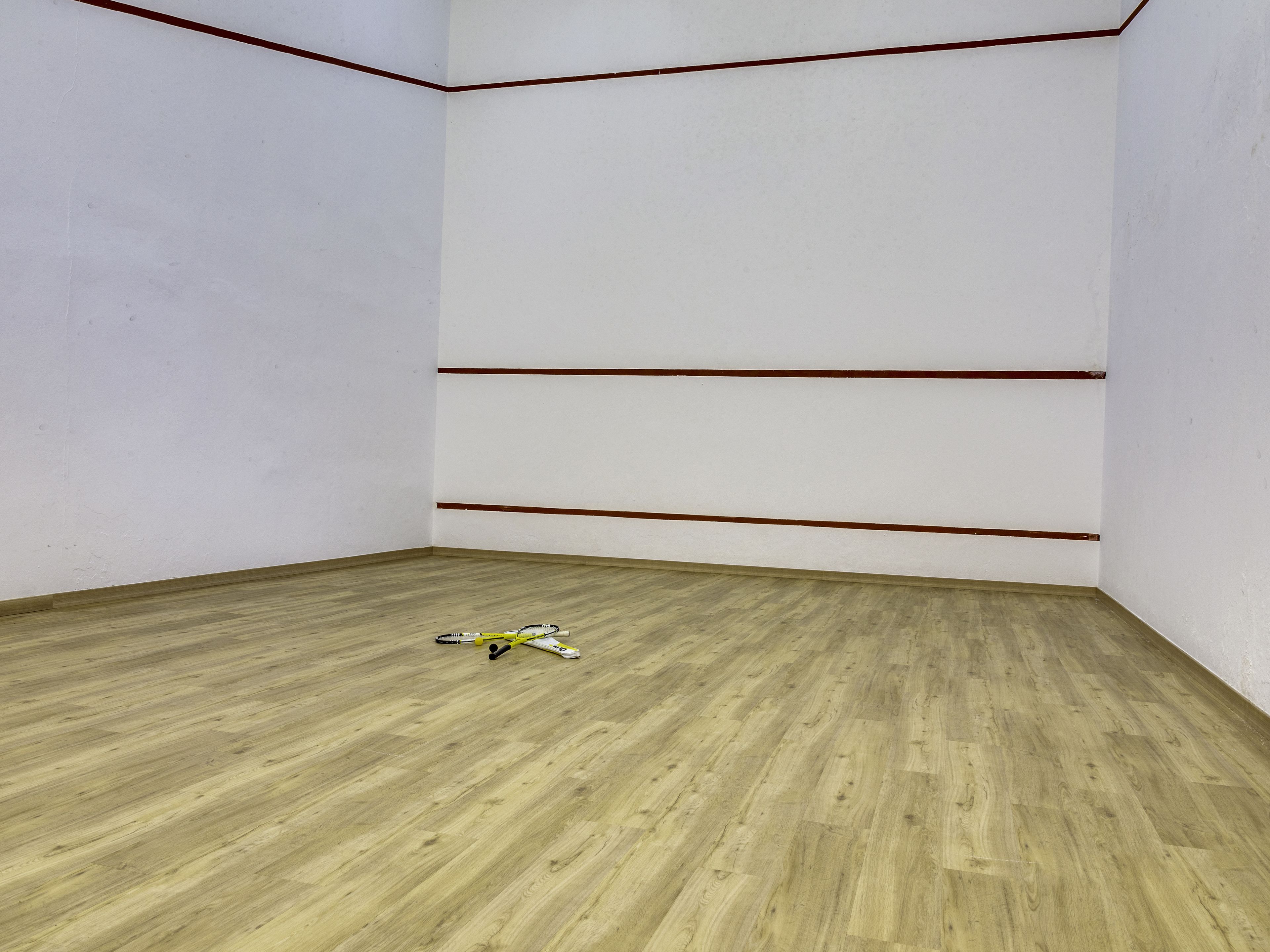 A room with a wooden floor, white walls, and red lines marking the boundaries.