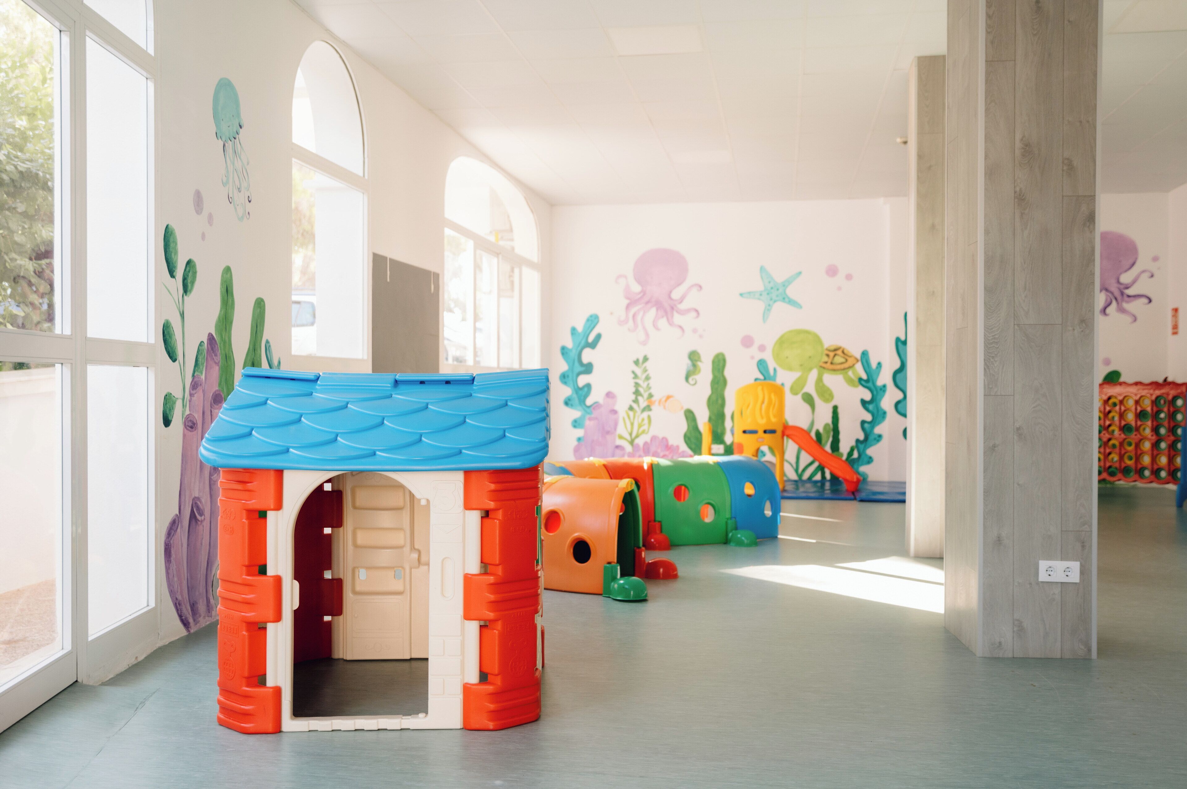 Ein Kinderspielbereich mit einem kleinen Haus und bunten Spielgeräten.