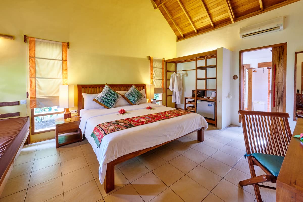 Un dormitorio amplio con una cama grande, cabecera de madera y una silla de madera.