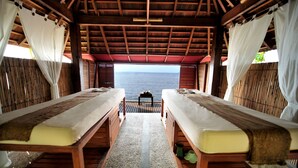 Una habitación con dos camas de madera, una pared de bambú y vista al mar.