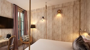 Een hotelkamer met een groot bed, een bureau met stoel, een televisie en een raam met gordijnen.