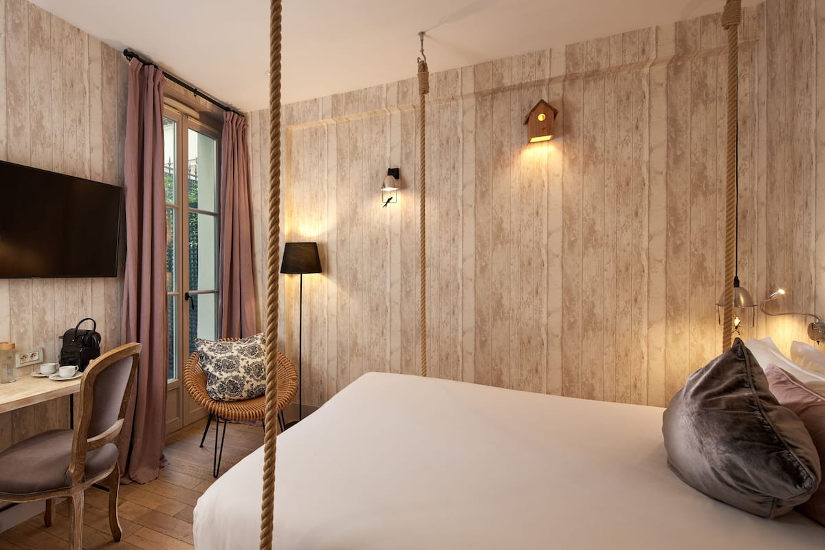 Una habitación de hotel con una cama grande, un escritorio con una silla, un televisor y una ventana con cortinas.