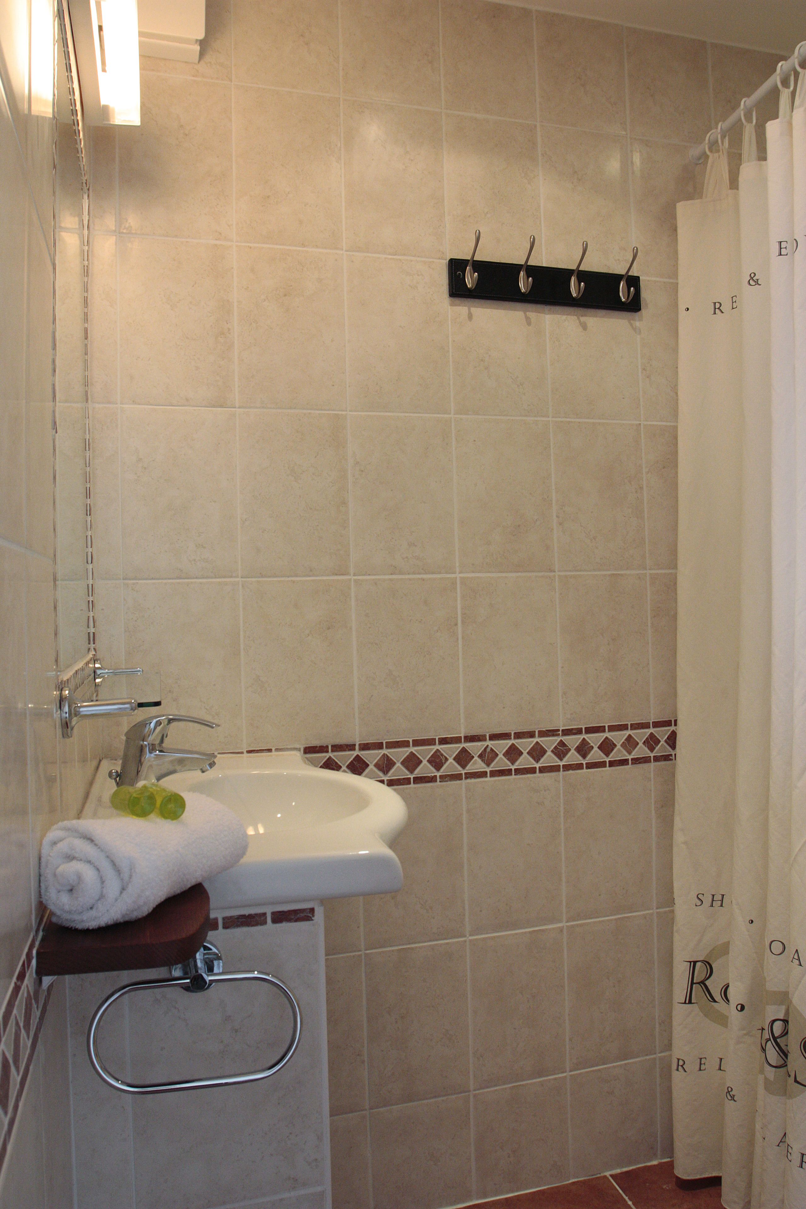 A bathroom with a sink, mirror, towel rack, and shower curtain.