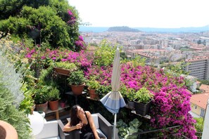 Un balcón con plantas en macetas y vista a un paisaje urbano.