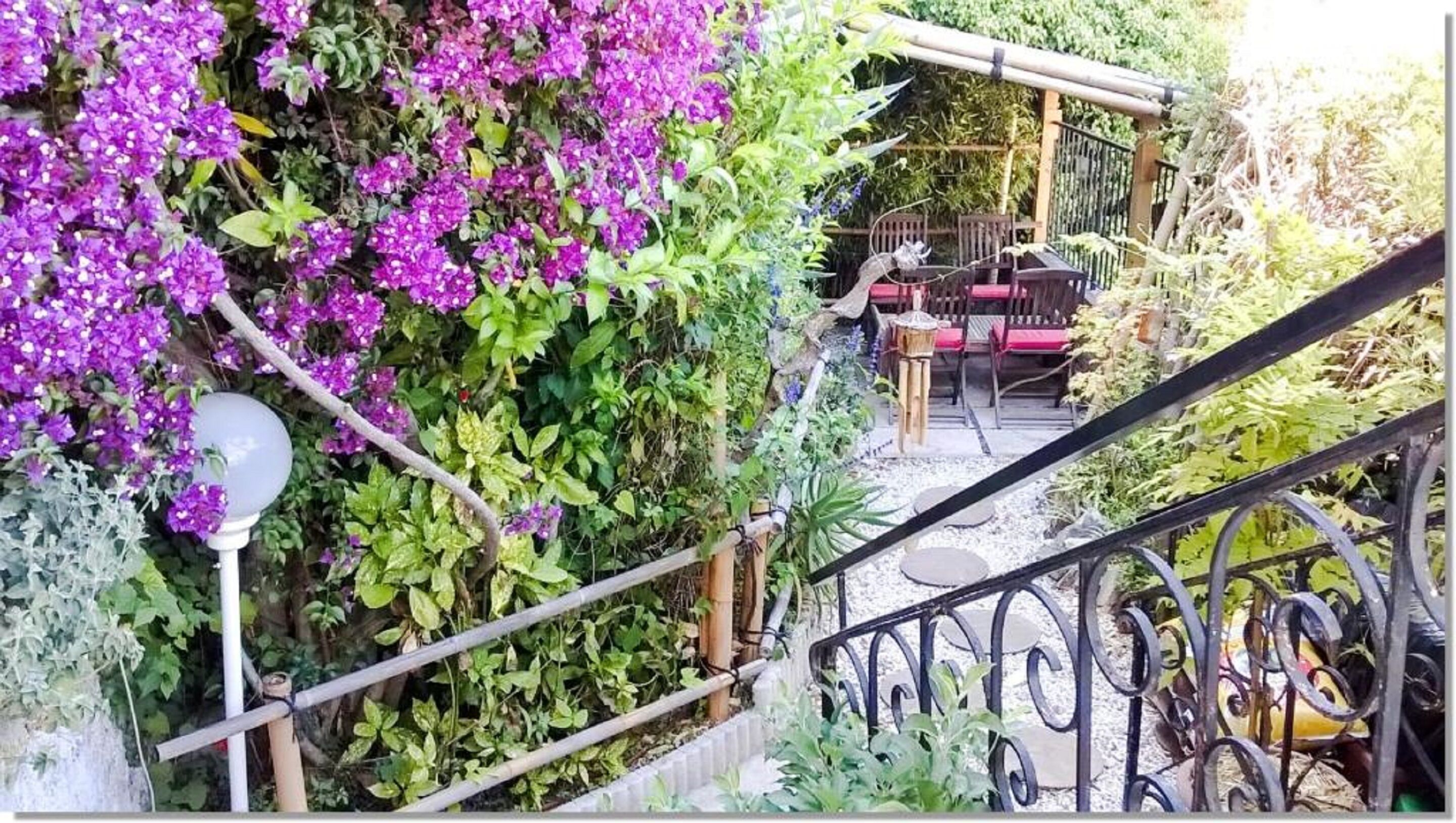 A garden with a staircase leading to a seating area with a table and chairs.
