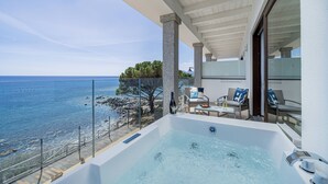 Een balkon met een jacuzzi, buiten meubels en uitzicht op zee.