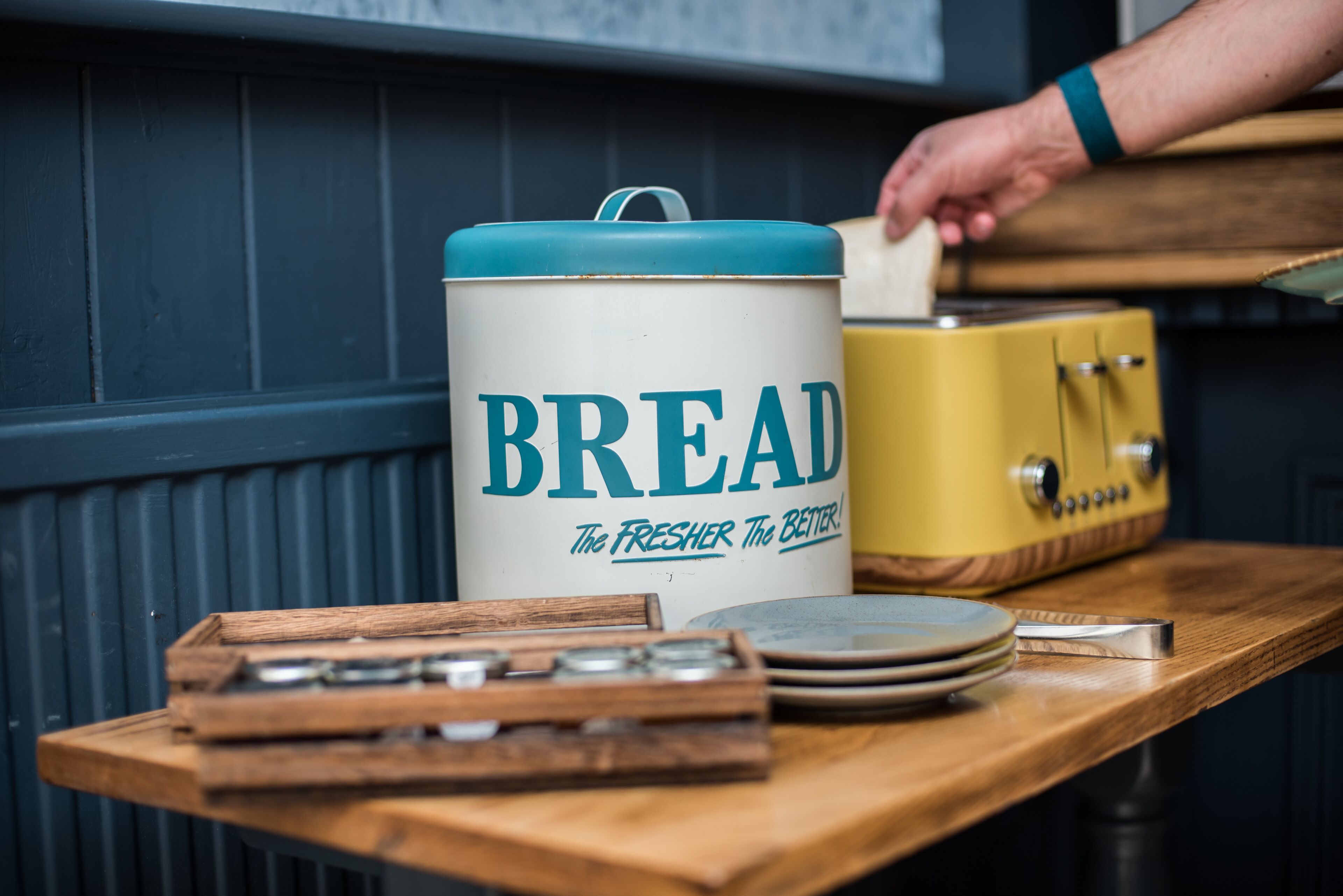A kitchen counter with a large white container labeled "BREAD" and a vintage yellow appliance.