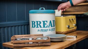 A kitchen counter with a large white container labeled "BREAD" and a vintage yellow appliance.
