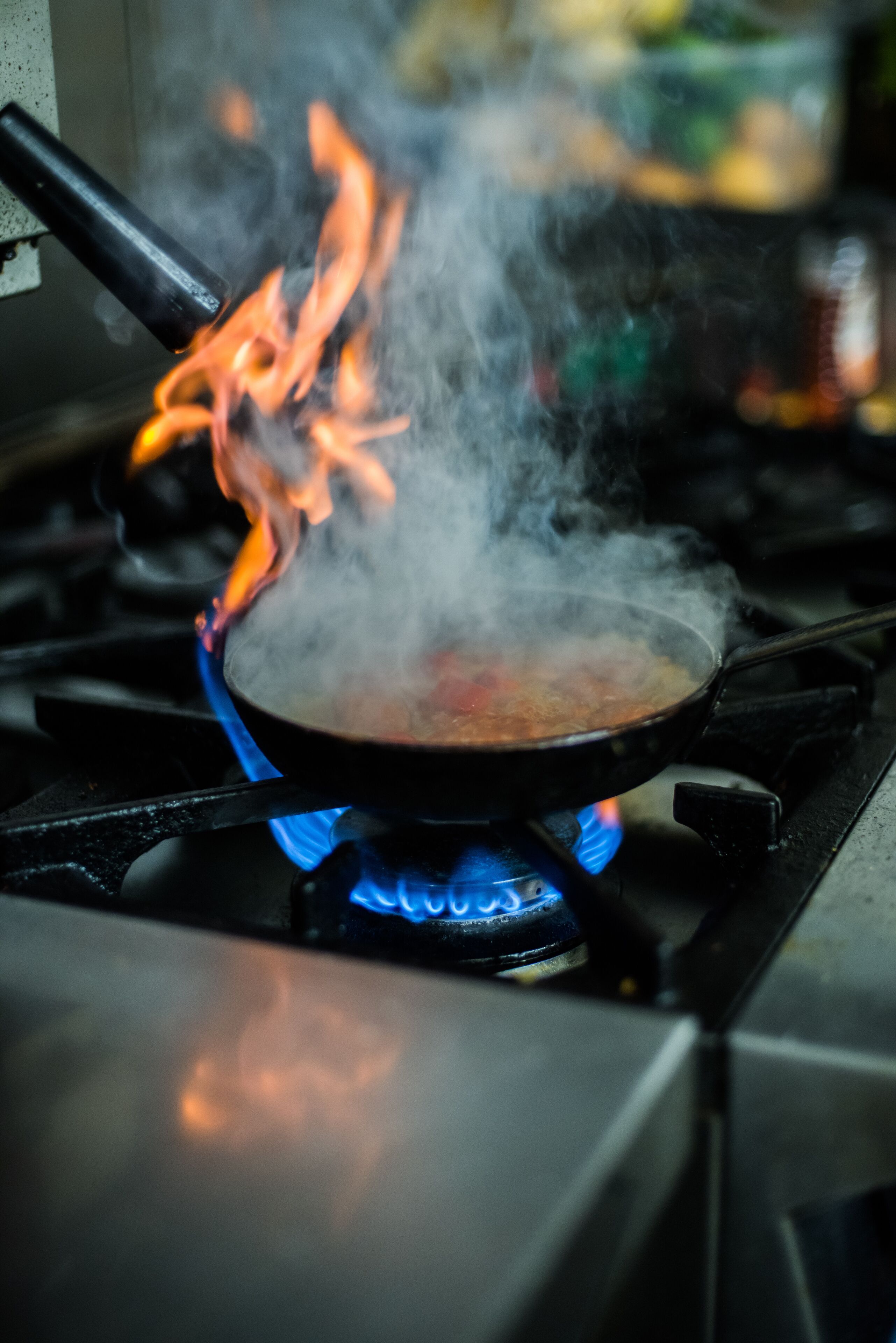 A stove with a pan on it, emitting steam and flames.