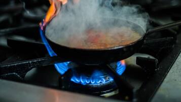 A stove with a pan on it, emitting steam and flames.
