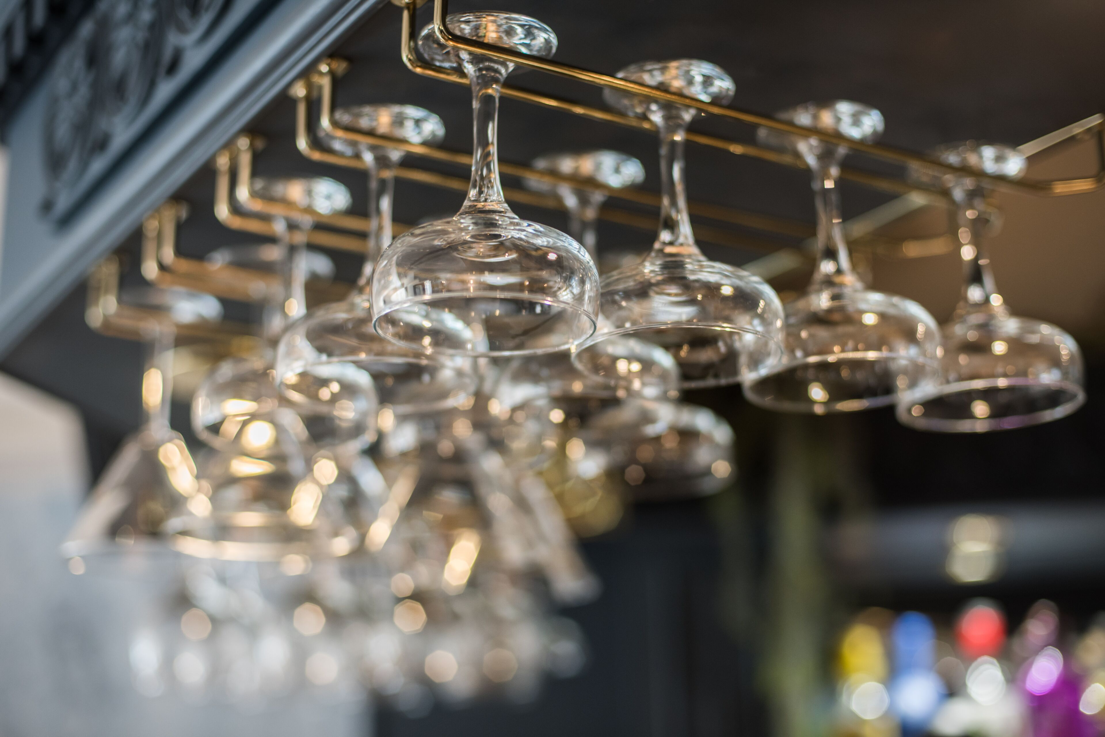 A collection of clear wine glasses hanging from a metal rack.