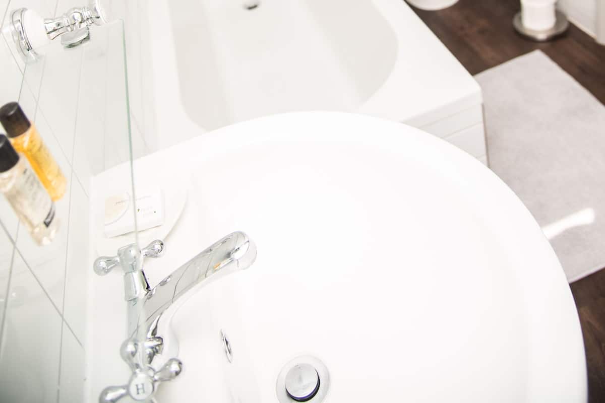 A modern bathroom with a glass-enclosed shower, a white bathtub, a toilet, and a sink.