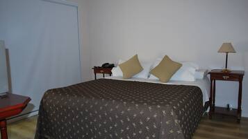 A neatly made bed with a patterned bedspread, a bedside table with a lamp, and a telephone on the nightstand.