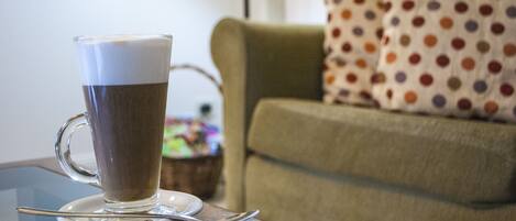 Una taza de café transparente sobre un platito, con una cuchara, sobre una mesa de madera.