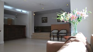 Amplia sala de estar con un mostrador de recepción, dos sillas y un jarrón de flores.