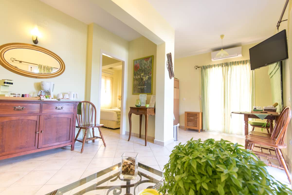 Una sala de estar con un mueble de madera, una mesa de centro de vidrio, una planta verde y un cuadro en la pared.