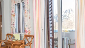 Un balcon avec une table et des chaises, une porte-fenêtre coulissante et une vue sur les montagnes.