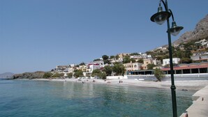 Une ville côtière avec des bâtiments qui bordent la plage, une eau d’un bleu limpide et un lampadaire.