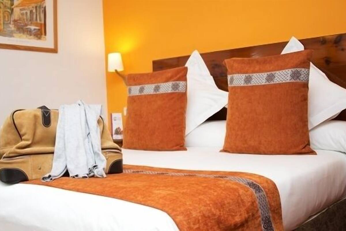 Une chambre d’hôtel avec un lit, une table de chevet, une lampe et un tableau au mur.