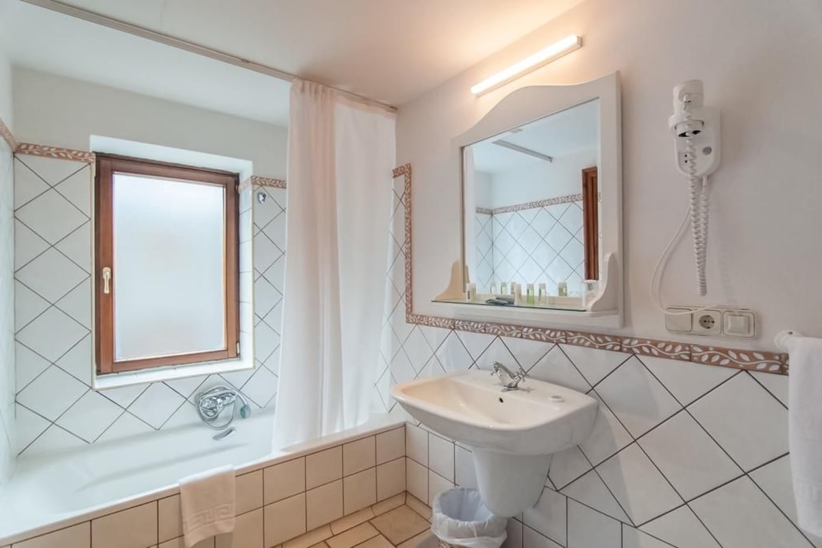 A bathroom with a sink, mirror, and window.