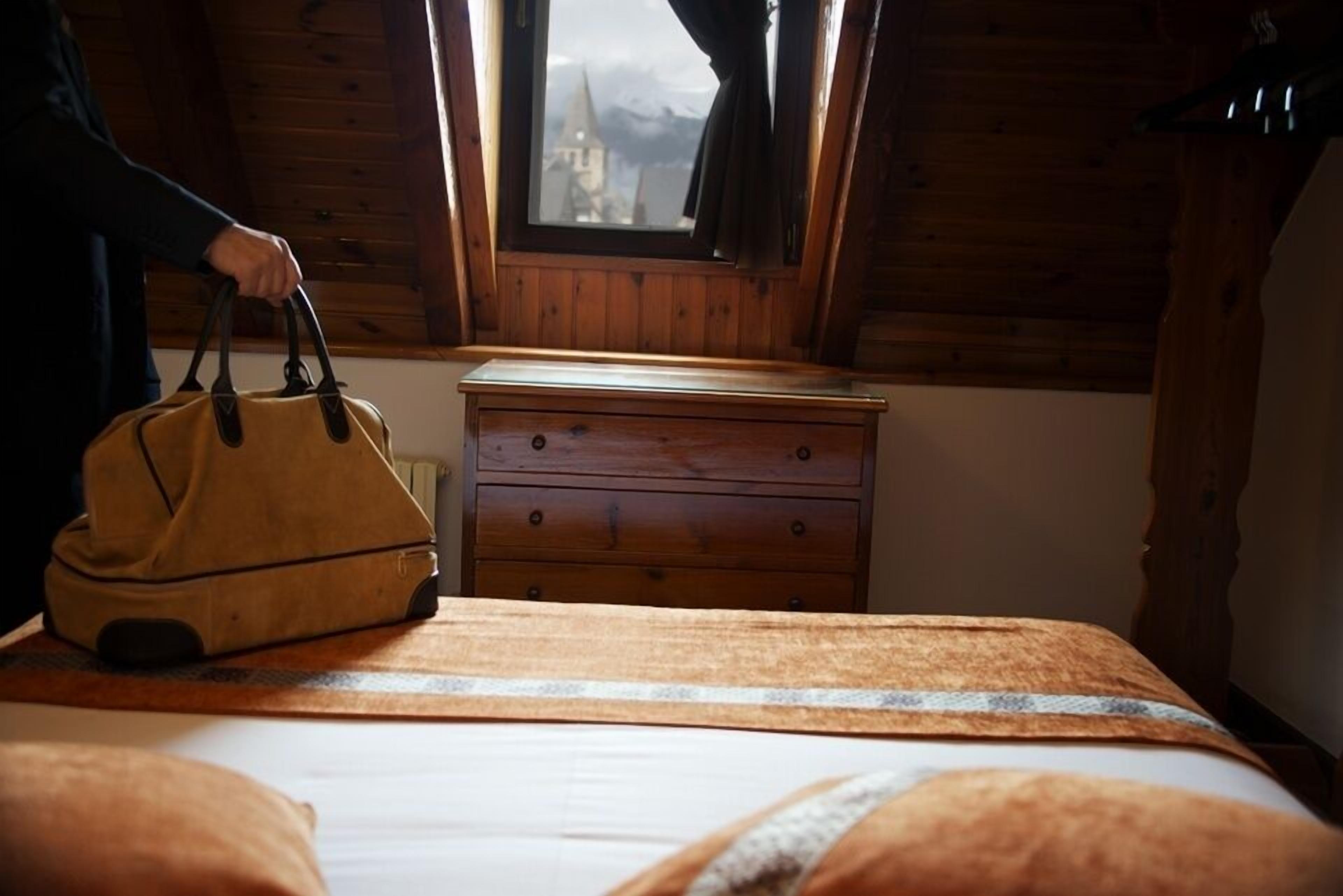 Une pièce en bois avec un lit, une commode et une fenêtre donnant sur un immeuble.