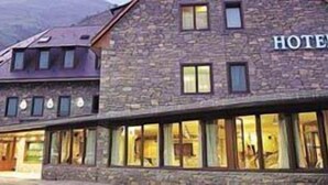 A stone building with a sign that reads "HOTEL" and large windows along the ground floor. - Hotel y Apartamentos Vilagaros (Naut Aran)