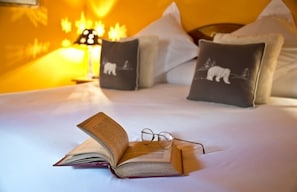 Ein Bett mit Buch und Brille darauf, umgeben von Kissen mit Tiermotiven.