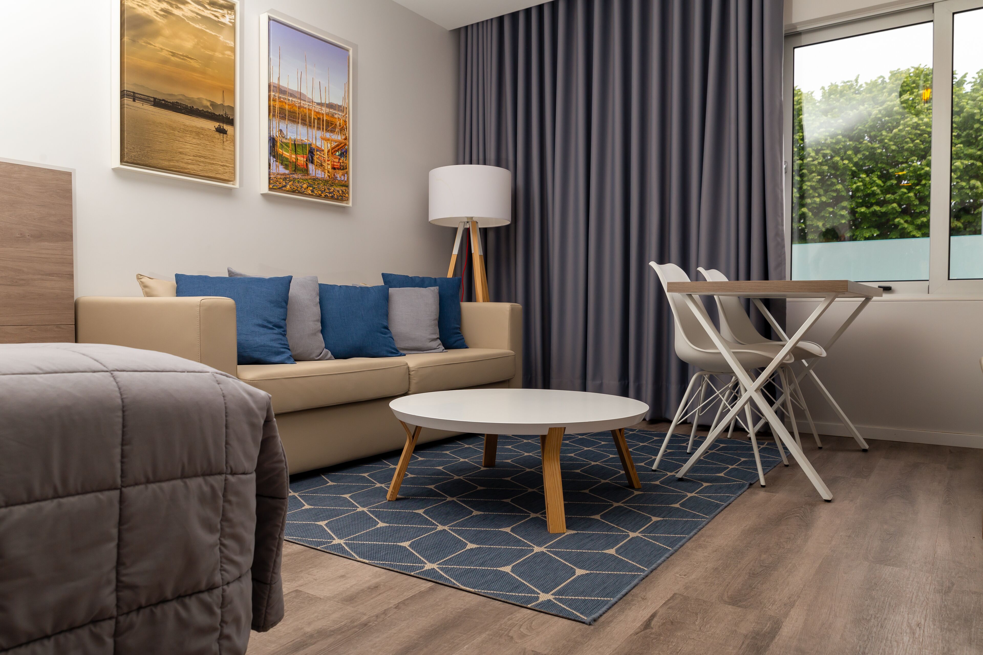 Habitación de hotel moderna con sofá, una mesa redonda, una lámpara y vistas al exterior.