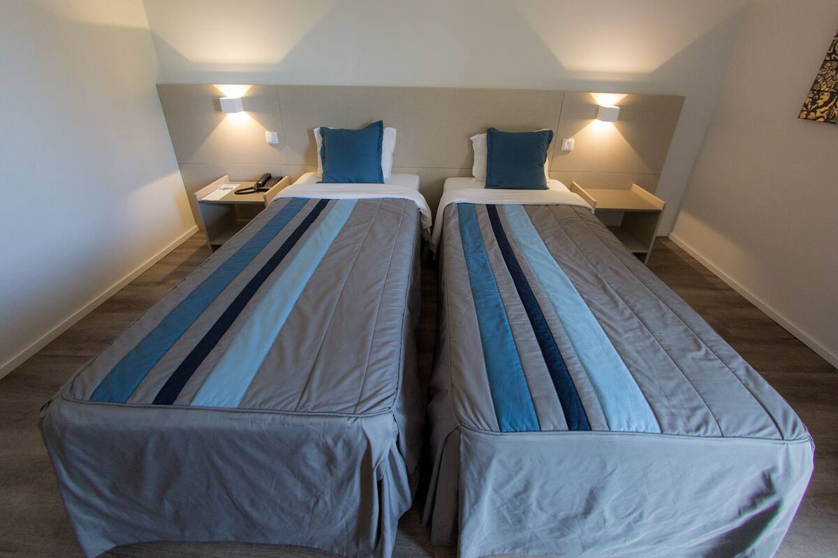 A twin room with two single beds, each with a bedside table and lamp.