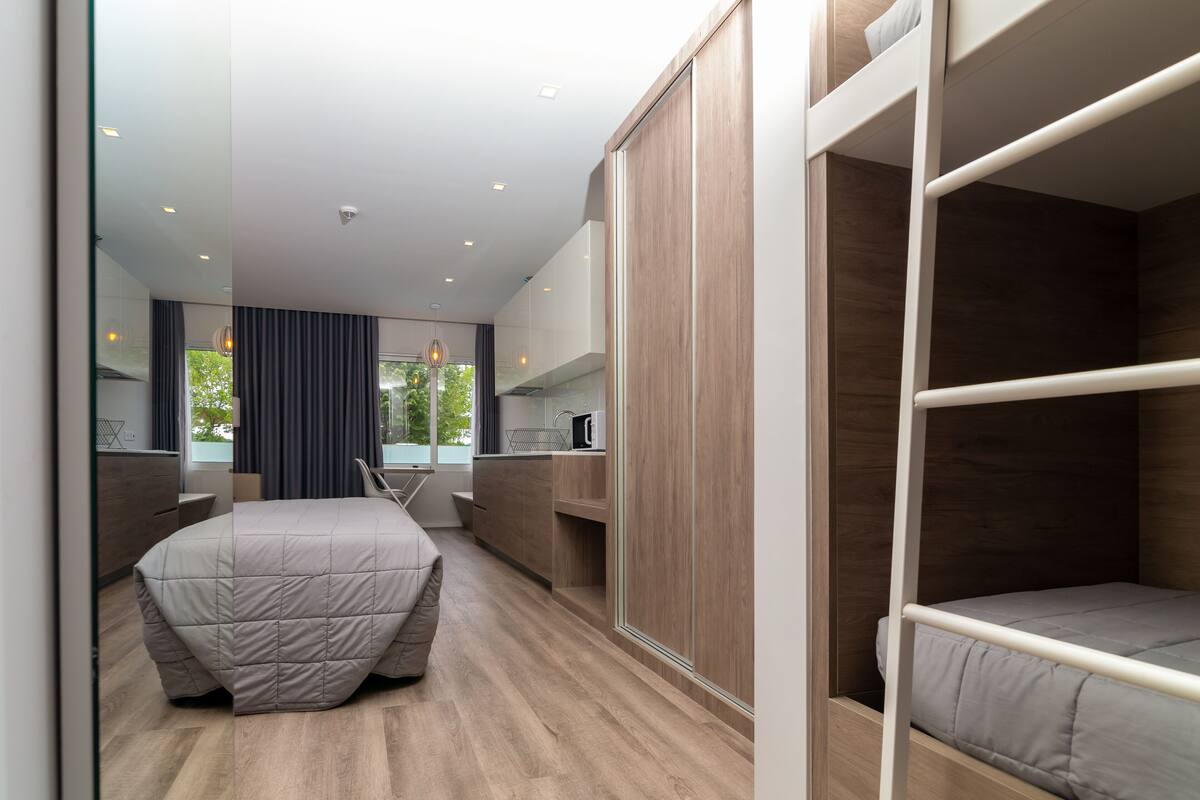 A modern hotel room with a bed, a desk, and a wardrobe.