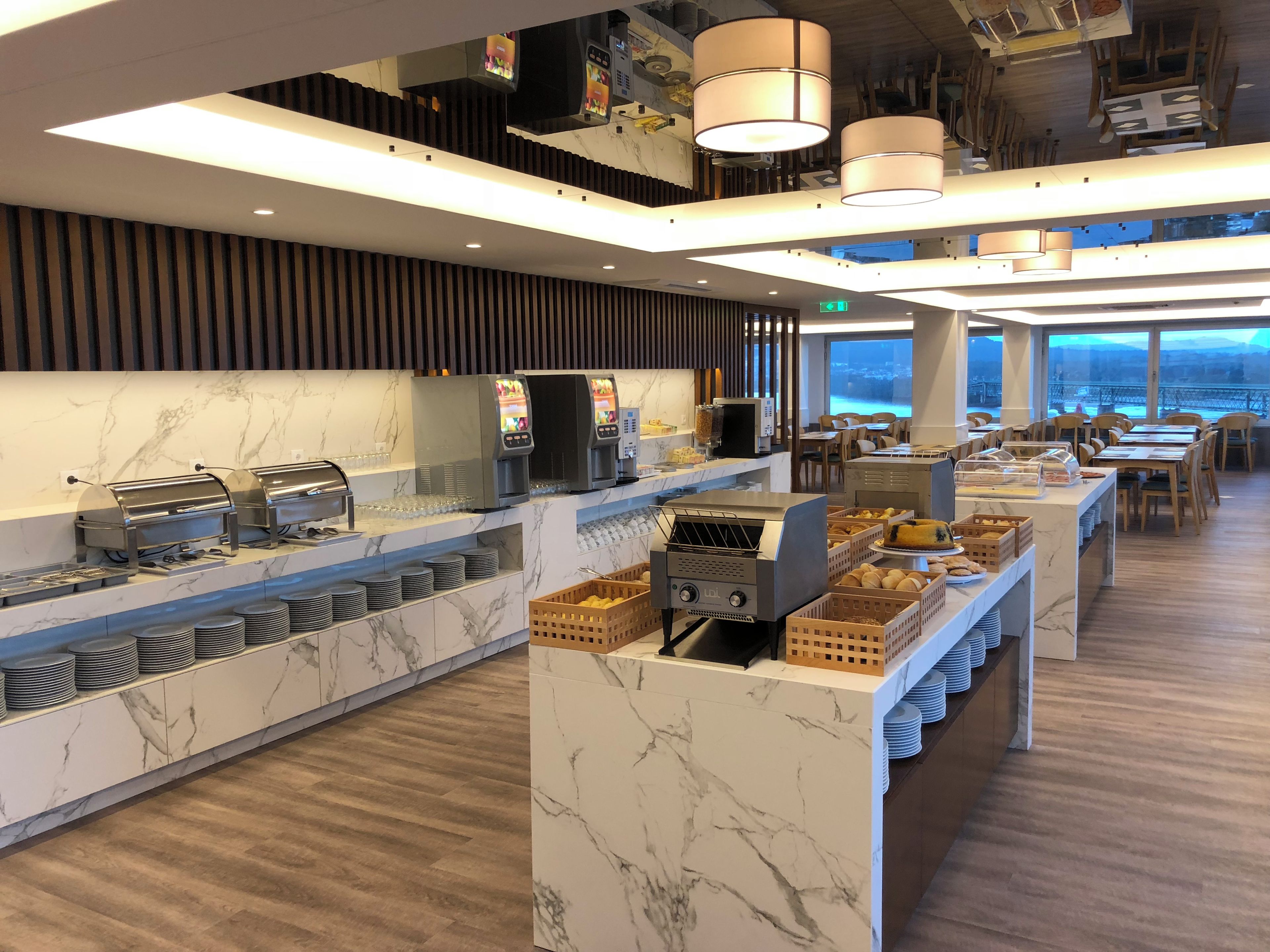 A modern buffet setup with self-service stations, a coffee machine, and a variety of food items.