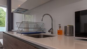 A modern kitchen with a stainless steel sink, a wire basket, a soap dispenser, and a microwave. - Do Parque - Viana do Castelo (Viana do Castelo)