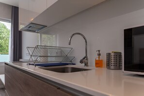 A modern kitchen with a stainless steel sink, a wire basket, a soap dispenser, and a microwave. - Do Parque - Viana do Castelo (Viana do Castelo)