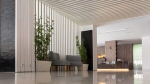 A modern lobby with a sleek, striped ceiling, a reception desk, and two grey armchairs. - Do Parque - Viana do Castelo (Viana do Castelo)
