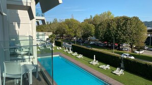 A modern hotel with a rooftop pool, lounge chairs, and a view of a parking area and trees. - Do Parque - Viana do Castelo (Viana do Castelo)