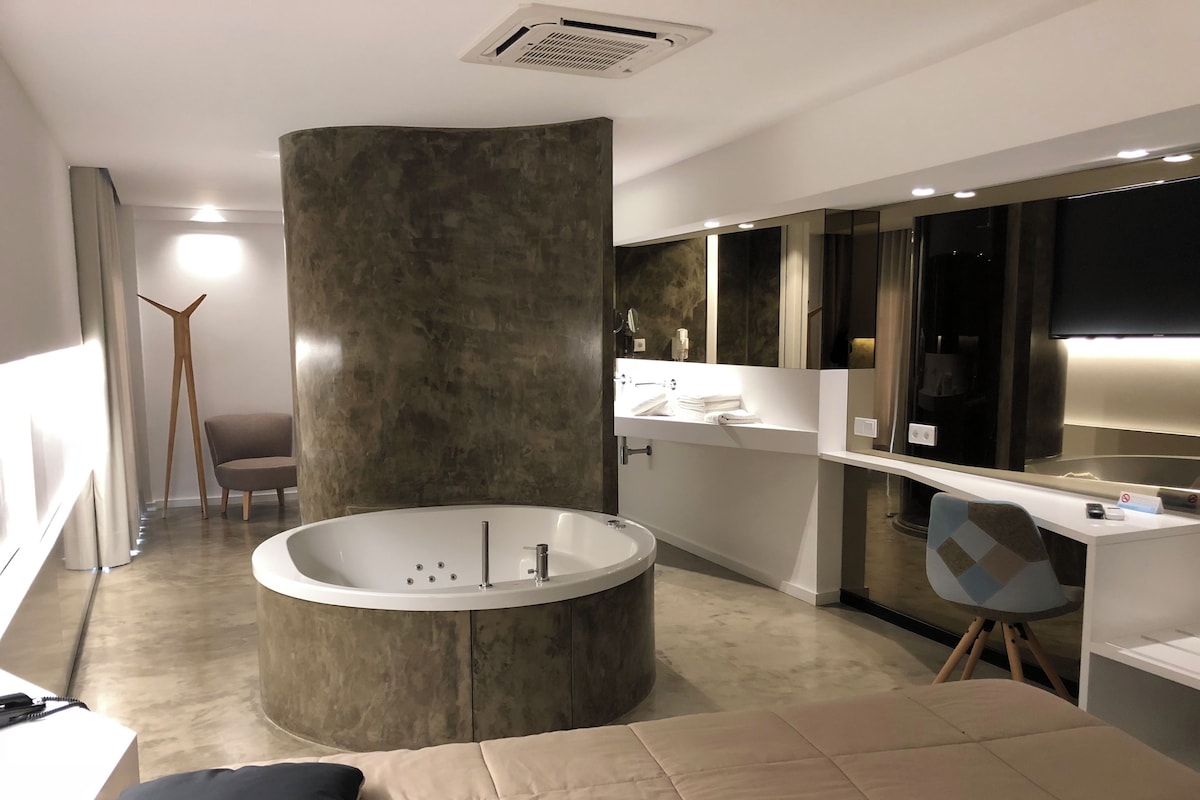 A modern bathroom with a freestanding bathtub, a vanity with a mirror, and a large window.