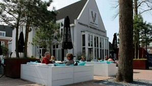Un hotel en un parque, con zonas de estar al aire libre y un restaurante.