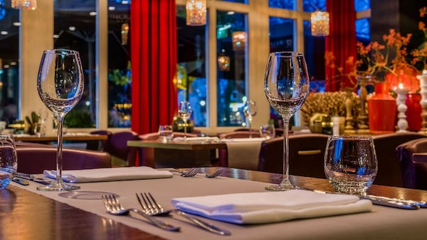 Un ambiente de restaurante con mesas dispuestas para comer, destacando copas de vino y cubiertos.