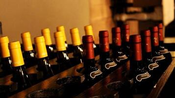 A row of wine bottles with yellow and red caps, arranged on a wooden rack.